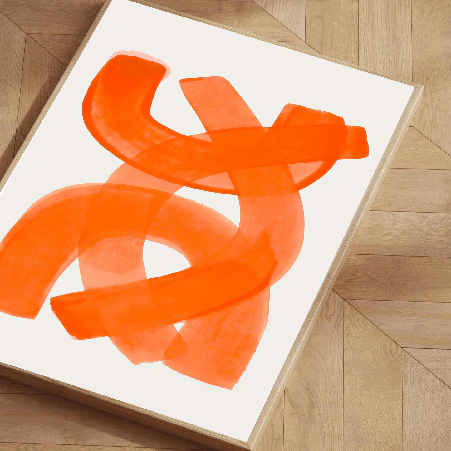 Abstract orange artwork on a white background, framed and leaning against a wooden wall.