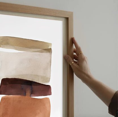 Person holding a wooden frame with abstract art inside