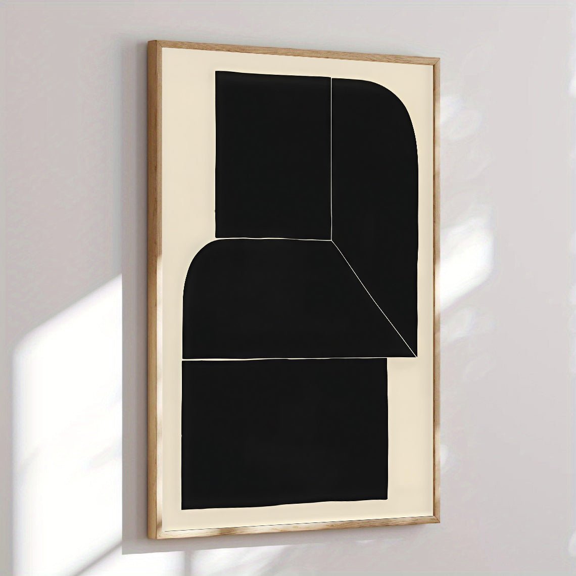 Abstract black and white artwork in a gold frame on a light gray wall