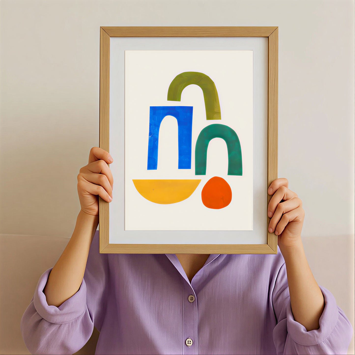 Person holding a framed abstract art print with colorful shapes against a plain background